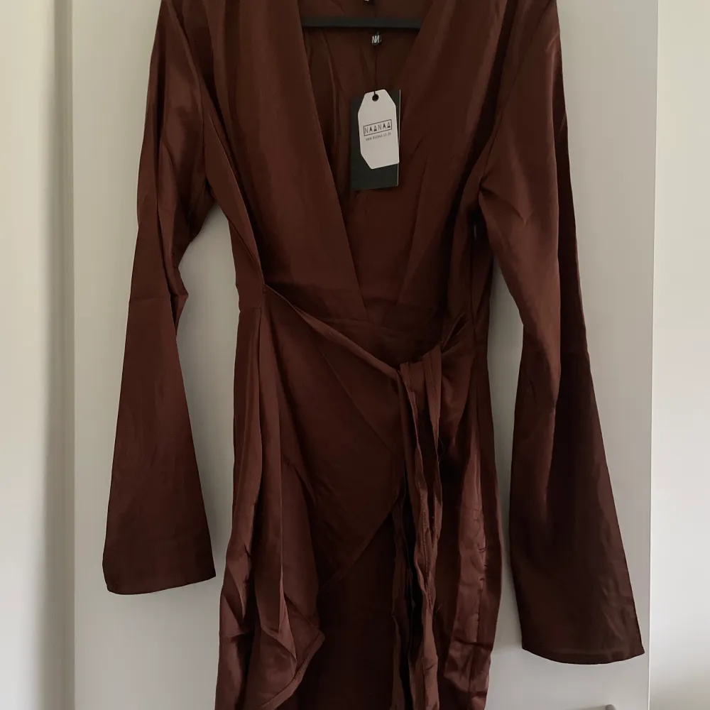 En brun oanvänd silkesklänning från Asos. Sitter väldigt fint runt kroppen och ett snöra där du kan reglera hur tajt den ska sitta vid midjan! 🤎. Klänningar.