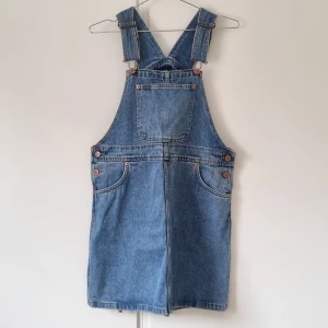 Jeansklänning - Jeansklänning med hängslen och fickor från Monki. Så snygg men är lite i det kortare laget för mig. Köpt second hand men i fint skick!  Material: 100% bomull 