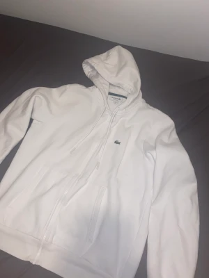 Lacoste  - Vit Lacoste hoodie i bra skick storlek L. Möts upp i Stockholm eller fraktar om det behövs.
