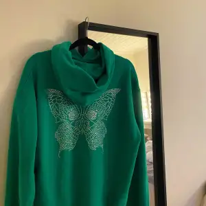 Grön hoodie med fjäril på ryggen från leccaci i storlek M.