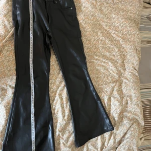 Utsvängda fake läder byxorna - 37cm midja 104 längd. Fett brallor med bootcutt 