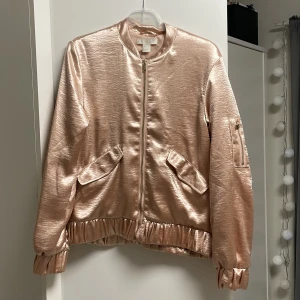 Satin kofta med dragkedja - Satin kofta med dragkedja från H&M i storlek 34, den är lite stor i storlek som man märker på bilden så det skulle även passa som storlek 36 också. Den har 2 fickor framme, och en ficka på högra armen. Helt ny och bara använd 1 gång. Jättefin material!!