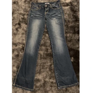 Lågmidjade flare jeans  - Snygga lågmidjade jeans i bootcut/flare modell med fina beiga detaljer!! Kan absolut skicka fler bilder om behövs!🫶 Innberbenslängden: 80 cm Midjemåttet: 38 cm (tvärsöver)