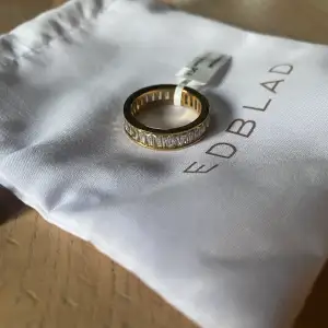 Edblad Radiant Ring Gold. 14 karat guldpläterat ring. Helt oanvänd. Lappen sitter kvar på och dustbagen finns kvar. Köptes för ca en månad sedan men inte använts. Storlek 8 (17,5 mm) Nypris 499 kr