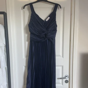 Balklänning - Marinblå plisserad lång balklänning i satin från Boohoo. Köptes förra året och endast använd en gång. Tillräckligt lång på mig som är 175.