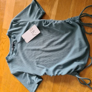 Topp från Zara - Jättefin tröja i turkos färg med snörningar på sidan. Aldrig använt och prislapp kvar.