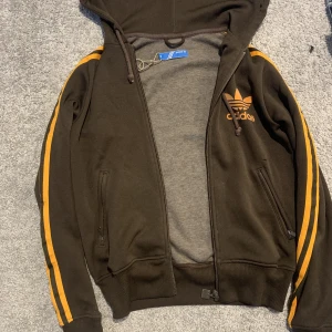 Adidas Zip hoodie  - En as snygg adidsss zip hoodie i färgerna organe o brun 😍brukar inte använda så mycket adidas kläder men denna är även fin till vardags och inte bara på idrottslektionerna i skolan ❤️rekommenderar för någon som bär Xs