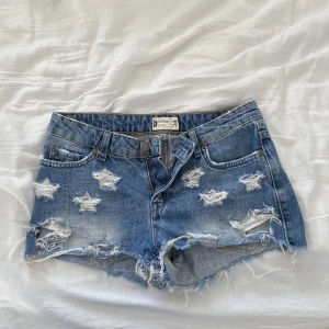 Jeansshorts - Lågmidjade jeans shorts med slitningar som "stjärnor" från Gina Tricot. Från en väldigt gammal kollektion. Kan tyvärr ej ta bild med de på då de blivit för små för mig! Mått rätt över vid midjan: 36cm