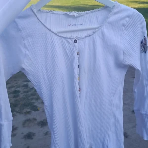 Långärmad vit tröja🤍 - Säljer denna för att den är för liten för mig, bra skick och inga fläckar.      Detaljer på ena armen som ni ser på bilderna. Enkel att styla med ett par jeans eller en kjol. Vi står för frakt. Skriv till mig om du har mer frågor om den🫶🏻🫶🏻 40kr +frakt