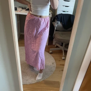Rosa blommig kjol - Rosa blommig långkjol. Jättefin men tyvärr lite liten i midjan för mig. Bra skick!