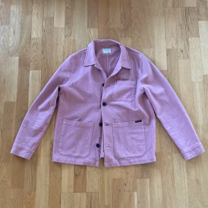 Overshirt i jeansmaterial - Overshirt i jeansmaterial från Nudie Jeans i storleken M. Färgen är pastellrosa och jackan är  knappt använd. 