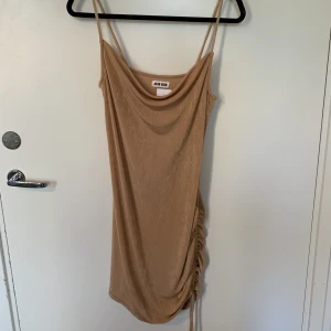 Festklänning - Snygg beige festklänning med knytning på sidan av benet, går till knäna i storlek M