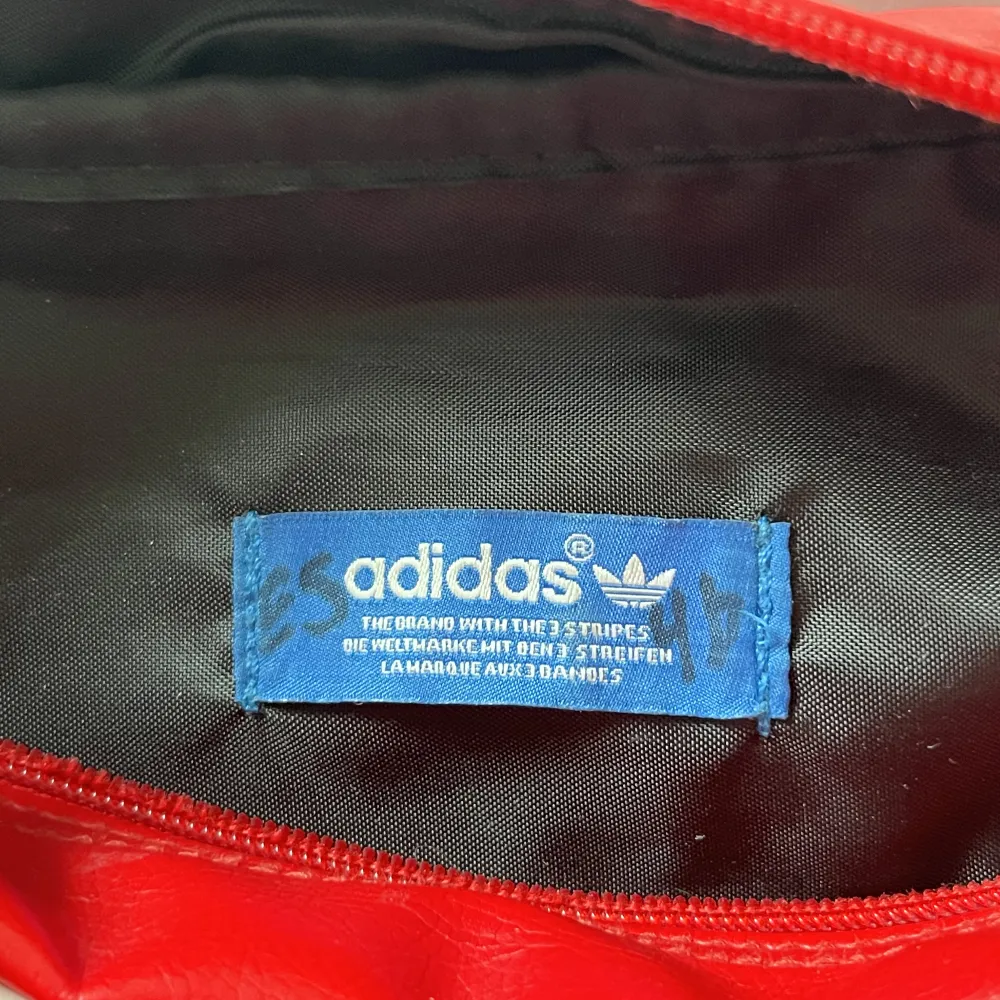 Adidas retro axelremsväska i röd. Väskan har några fläckar men i övrigt i bra skick. . Väskor.