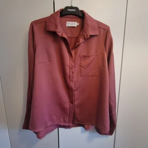 Mörkrosa skjorta från Nakd - Mörkrosa skjorta från Nakd. Tjockare satinliknande material. Vida ärmar. Storlek S