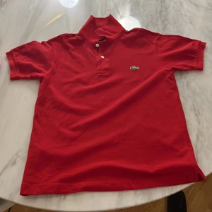 Piké Lacoste  - Röd Lacoste piké. Storlek 2 ca 164 cm