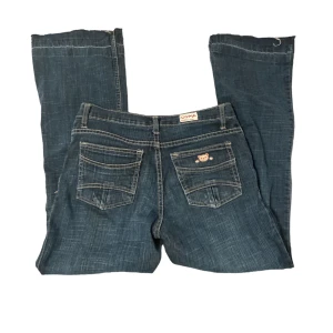 Bootcut jeans - vintage bootcut jeans med en söt detalj på bakfickan.   Innerbenslängd: 74,5 cm Midjemått runtom: 77cm