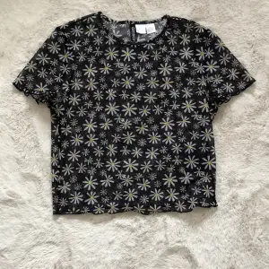 En blommig ”genomskinlig” svart t-shirt som är skön på sommaren 