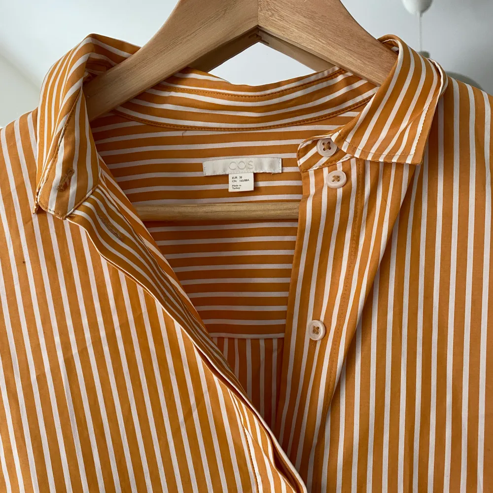 Säljer min fina blus/skjorta då den aldrig kommit till användning. Använd max 5 gånger. Vit och orange randig med en ”knytning” runt ryggen. . Blusar.