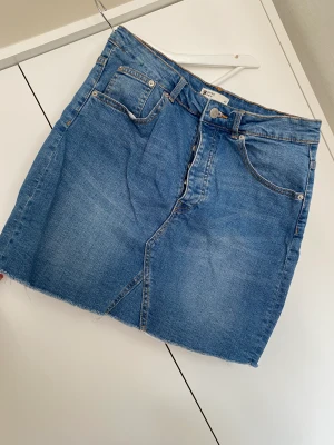 Jeanskjol - Jeanskjol från Gina tricot i en mellanblå färg. En rå nedre kant på kjolen för en sliten look. Lite stretch men annars true to size. I bra skick och nytvättad. Dålig bild med den på då det är flera år sen jag använde den. 