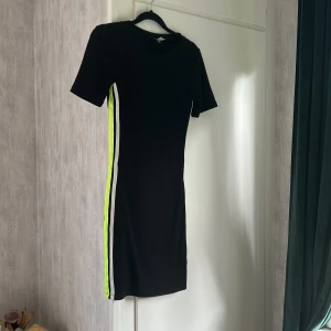 Svart klänning  - Svart klänning med vit gula ränder på sidorna, endast använd ett fåtal gånger