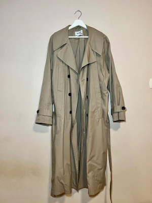 Trenchcoat, kappa - Säljer min trenchcoat som har använts några få gånger, 3-4 ggr. Den är som ny och är köpt från weekday. Den är i oversize och i storlek M samt unisex! Säljs i uppsala och Stockholm.