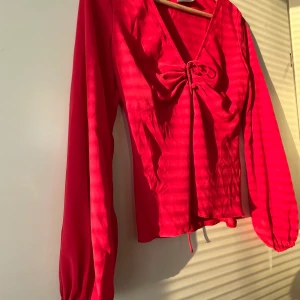 Röd blus  - Röd blus med scrunched ärmar och snörning vid urringningen. Tunt och lätt material. Använd fåtal gånger, nästan helt nytt skick 