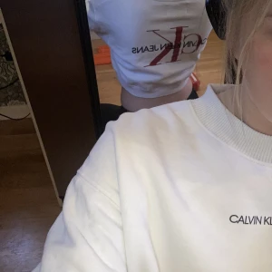 Hoodie  - En croppad hoodie från Calvin Kline jeans med tryck i ryggen. Den kostar ungefär 400 kr ny och är nästan oandvänd.