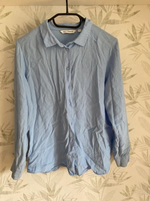 Skjorta  - En ljus blå skjorta men knappar, inte använt mycket.