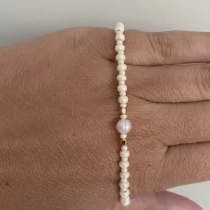 Handgjort armband i beige och guld  - Handgjort armband med guldiga inslag. 