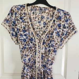 Blommig omlett klänning - Blommig blå klänning med omlett korsning runt midjan, oanvänd