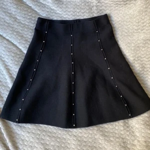 Kjol - Svart kjol med silver detaljer, sitter tajtare upptill, utsvängd 