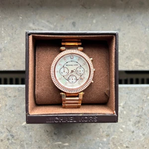 Michael Kors Klocka - Michael Kors Parker Vit/ Roséguldstonat stål 39 mm.  Fick den i present och har max använt den 1-2 ggr. Utmärkt skick. Jag la märke till att den har en jätte liten skråma på glaset men den är svår att se med blotta ögat. Länkar medföljer. Nypris: 2995 kr