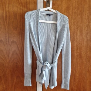 Tommy Hilfiger långkofta ljusblå - Kofta i ljusblå/babyblå från Tommy Hilfiger. Storlek S. Har knytband i midjan, som även går att ta av. Har lite noppror men är i fint skick annars.