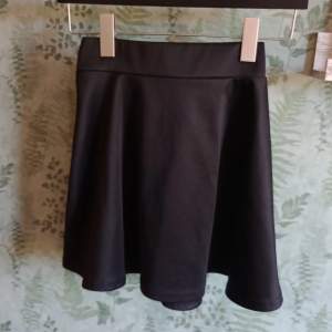 svart kjol med glansig yta och stretchig midja. Köparen betalar frakt 