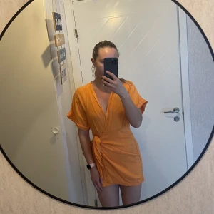 & other stories omlottklänning orange 36 - Säljer en jättefin orange omlottklänning från & other stories. Storlek 36. Jätte fint skick! Väldigt kort, jag är 165cm och den går strax nedanför rumpan på mig.