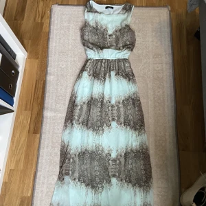 Lång blågrå klänning-Vero moda - En klänning i väldigt bra skick! Från vero moda, den är lång till fötterna. Relativt tunn men endå täckande och kan användas på höst! 