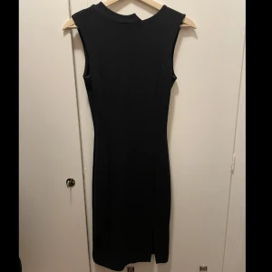 Svart klänning Whyred - Svart klänning med split på vänster sida. Använd några gånger men den är i fint skick. Har en liten defekt som knappt syns vid spliten nertill.