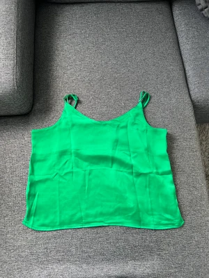 Grön silkes topp/ linne - Grön silkes topp från Zalando (JJXX). Använd en gång så i perfekt skick! I storlek XL men väldigt liten i storlek så hade passat L-M