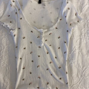 Blommig topp med spets - Jättesöt blommig kortärmad top med knappar och spets. Väldigt mycket brandy stil över den🤩💗 Storleken är xxs men skulle säga att den passar xs☺️ Perfa till sommarn!! 