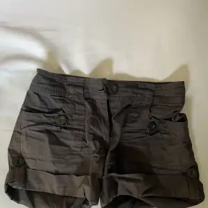 Ett par bruna shorts med mycket fina knappar och detaljer 🤩Shortsen är i bomull och har två extra knappar som sitter fast på insidan som man ser på bilden 👍🏼:)