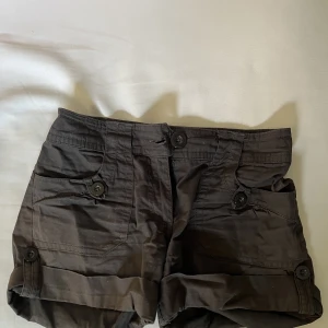 Shorts - Ett par bruna shorts med mycket fina knappar och detaljer 🤩Shortsen är i bomull och har två extra knappar som sitter fast på insidan som man ser på bilden 👍🏼:)