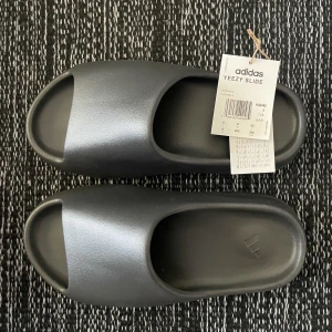 Yeezy Slide ’Onyx’ i size 42 - Nya & oanvända Yeezy Slide ’Onyx’ i storlek US8 = EU42. Digitalt kvitto finns från adidas CONFIRMED. Skickas dubbelboxade i originalkartonger. Köparen står för eventuell frakt. Kontakta för fler bilder eller vid frågor.