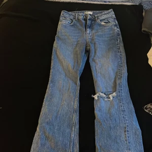 Jeans med hål - Säljer dessa jeans från Gina i storlek 34 som är flare med hål på vänstra benet i midwaist. Ni kan skriva privat om ni vill ha flera bilder.