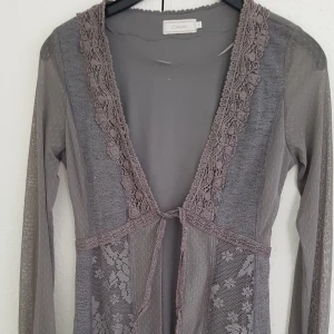 Lång kofta  - Säljes pga av fel storlek aldrig använd. Nyskick  Lång kofta i tunn material och fina detaljer knyts i mitten rök och djur fritt hem  Nypris 1100