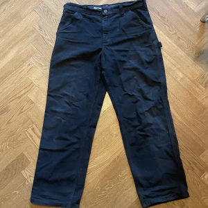 Vintage Carhartt carpenter pants - Ett par vintage svarta carpenter pants från Carhartt. Storlek 34x30 (men passar bra för de som har 32 i längd). Några få små färgfläckar här och där, annars inget. Lätt använda. Tvättar innan jag skickar. Meddela för fler bilder!