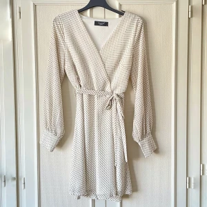 Prickig klänning - Prickig klänning från Sisters Point med långa ärmar och ”fejkad” omlott. Stängs med dragkedja i sidan. Köpte den second hand men säljer då jag endast använt den en gång. Ingenting att anmärka på direkt ☺️