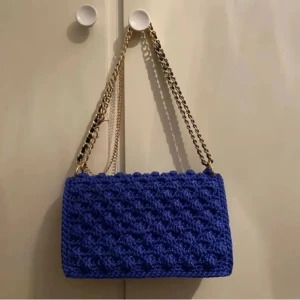 Bubbel väska - Virkad väska i royalblå, i bubbelformat. Garnet är gjort på "hård polyester". Stängs igen med hjälp av en tryckmagnet. Ej fodrad! Mått: längd: 25.5cm höjd: 15.5cm djup: 4cm  Frakt tillkommer♥️ OBS! Katter finns i hemmet