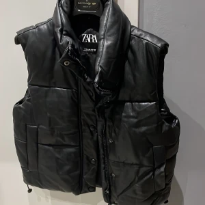 Svart skinnväst🪩 - Säljer denna jättefina svarta västen från Zara😍köpt för ca 3 år sedan men är använd fåtal gånger och är i jättefint skick! Är i storlek XS, men skulle säga att den är mer en S!
