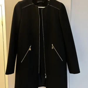 Svart ursnygg jacka - Svart ursnygg kraglös jacka säljes p.g.a den var lite för liten. Kan både kläs upp och kläs ner. 