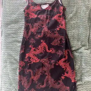 Svart knälång klänning med rött drakmönster. Aldrig använt